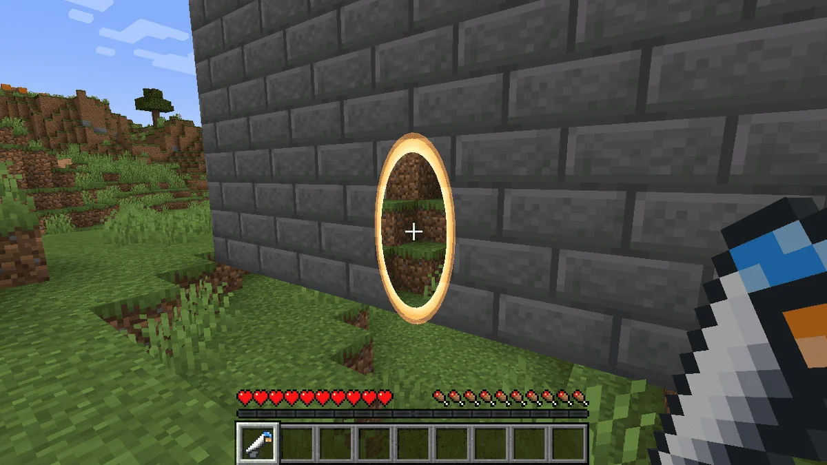 An orange portal in a Minecraft stone wall with the portal gun equipped