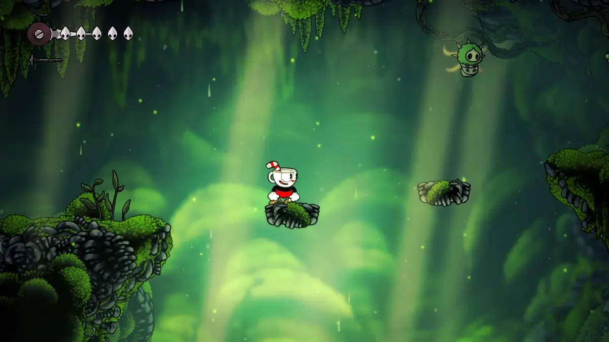 Cuphead standing on a small mossy platform in a green cavern with a Silksong-style HUD